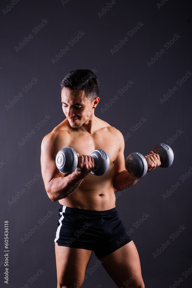 Shirtless bodybuilder showing his great body and holding dumbell. Shirtless bodybuilder showing his great body and holding dumbell.