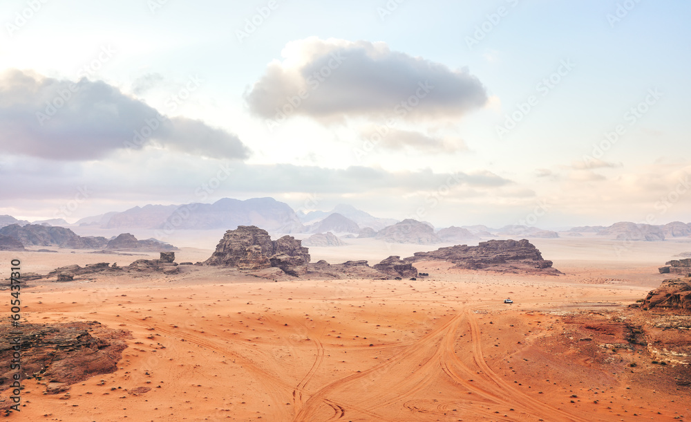 Red orange Mars like landscape in Jordan Wadi Rum desert, mountains background overcast morning, small vehicle distance for scale. This location was used as set for many science fiction movies