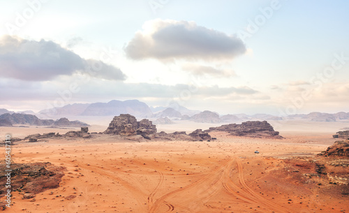 Red orange Mars like landscape in Jordan Wadi Rum desert, mountains background overcast morning, small vehicle distance for scale. This location was used as set for many science fiction movies © Lubo Ivanko