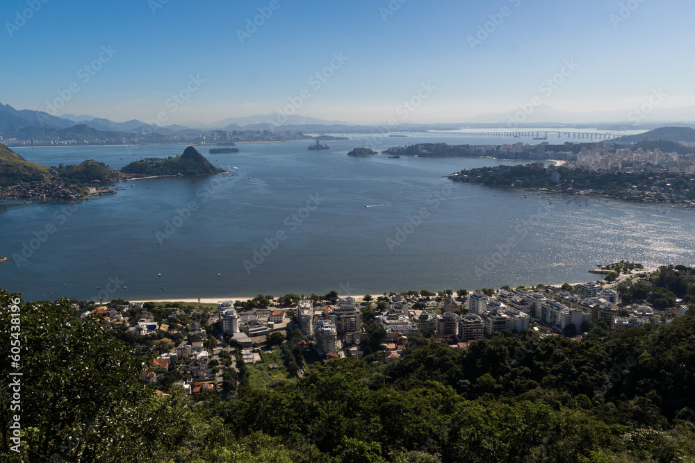 Beautiful view of Rio de Janeiro, Brazil seen from Niterói. With many hills in the background, Guanabara Bay, Jujuruba, Rio Niterói Bridge, Christ the Redeemer, beaches, pier with a boat. Sunny day
