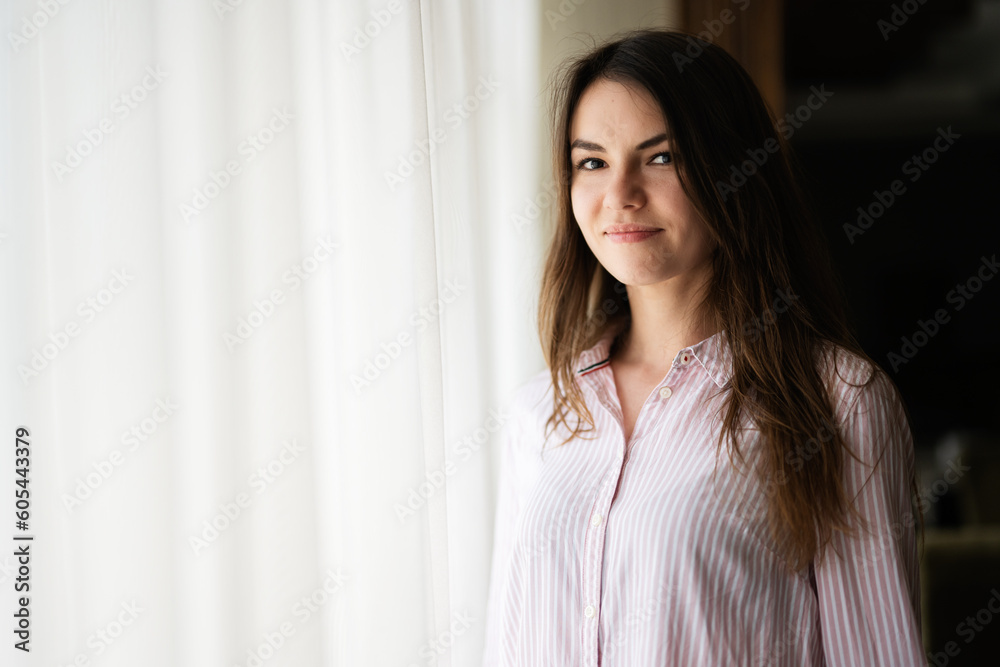Young beautiful brunette woman at the window light background. Young beautiful brunette woman at the window light background.