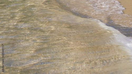 Sandy beach, lit by sun, sea water washes over, closeup detail - abstract shallow depth of field tropical vacation background photo