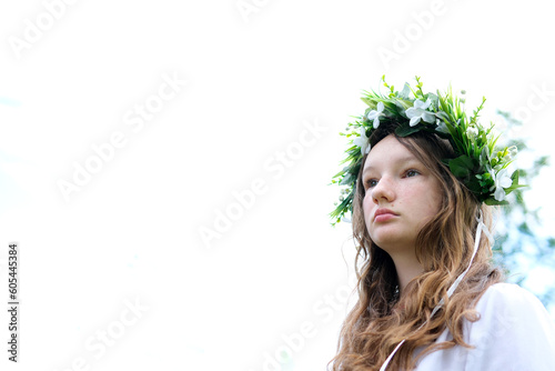 on white background face of beautiful young Ukrainian woman in wreath of lilies of valley woven with green plants of flowers place for text we stand strong Victory from importance of invincibility photo