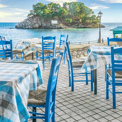 Traditional tavern restaurant with empty tables and chairs in front of Panagia island in Parga, Greece, Europe.