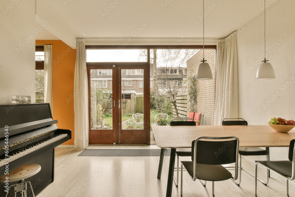 a living room with an open door and piano in the fore - image is taken from inside to outside,