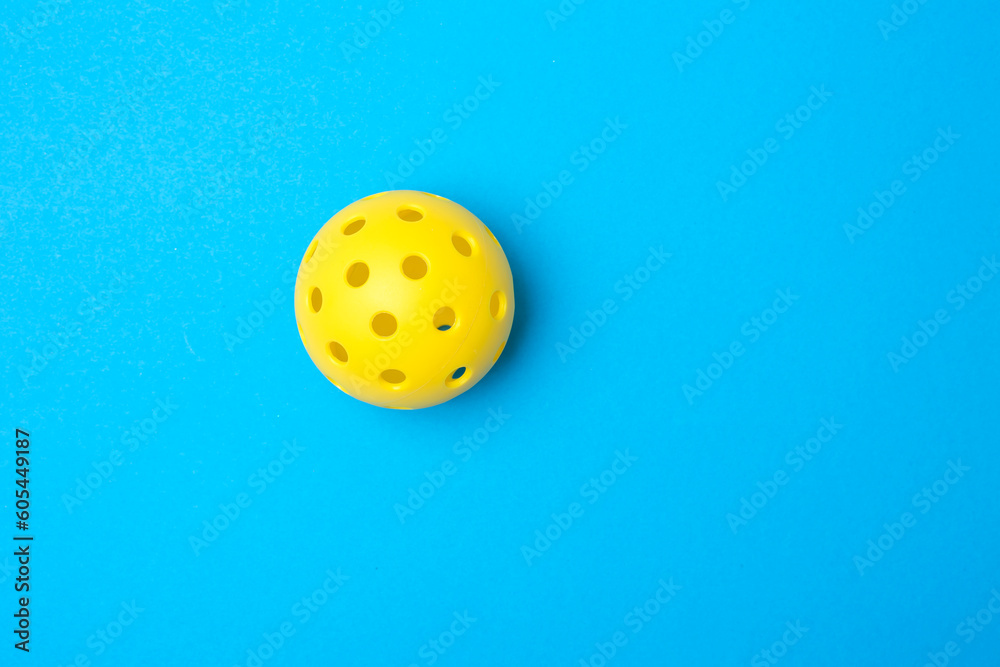 Yellow pickleball ball on blue background. Horizontal education and sport poster, greeting cards, headers, website.