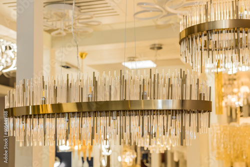 A luxury classic style chandelier is installed on the ceiling of the room. The metal frame is a yellow gold color. Concept of interior decoration. Indoors. Close up.
