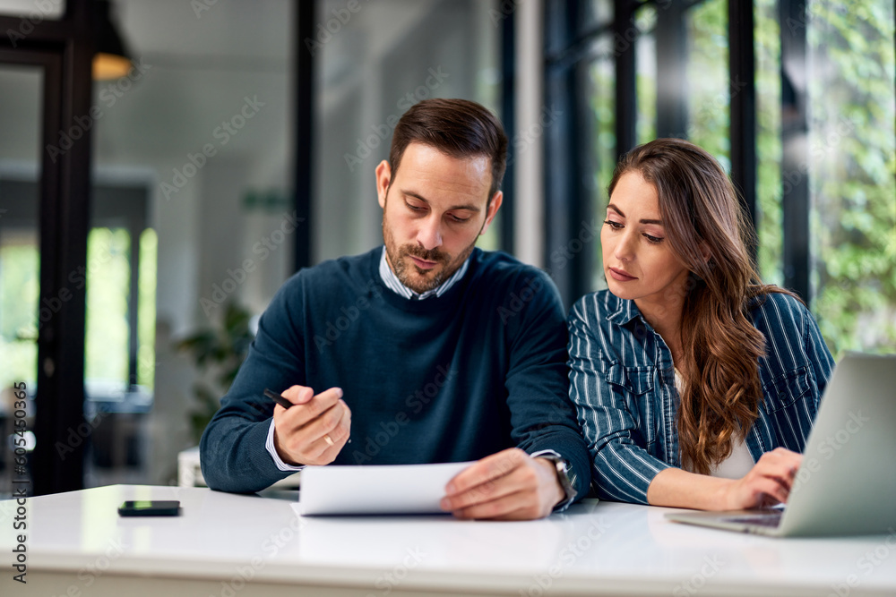 Two serious business people looking at work reports or business plans at the office. Two serious business people looking at work reports or business plans at the office.