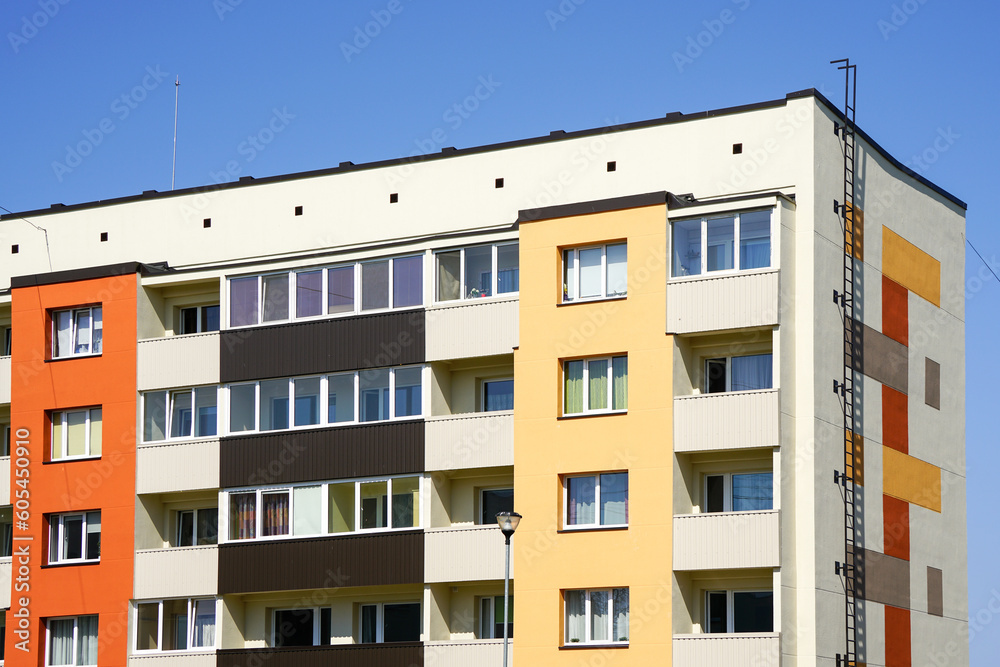 Renovated and insulated multistorey apartment building facade fragment against a blue sky background