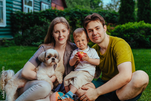 Young parents with one year child and dog sitting on the property