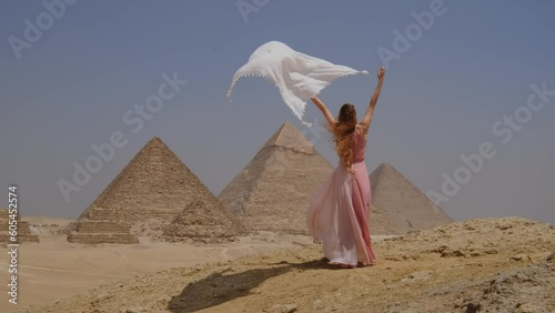 Young woman standing and watching the Great Pyramids of Giza in Egypt. 