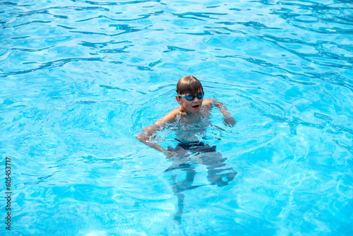 Underwater teen boy in the swimming pool with goggles in sunny day. Children Summer Fun. Kids water sport activity on summer holiday.