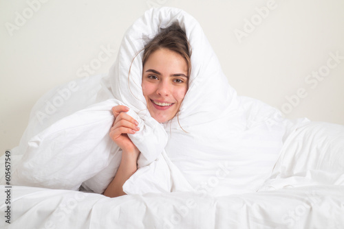Funny morning wake up. Beautiful young woman covered with warm blanket on bed at home