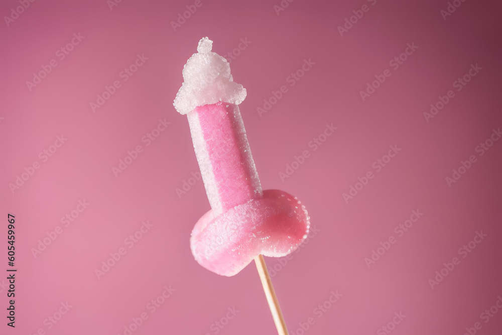 Pink sugary lollipop in form of penis on stick on a pink plain background Pink sugary lollipop in form of penis on stick on a pink plain background