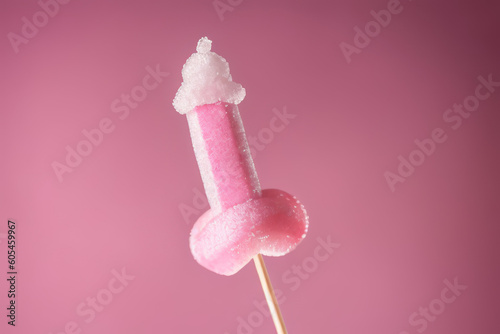 Pink sugary lollipop in form of penis on stick on a pink plain background photo