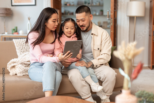 Chinese Parents And Little Baby Using Tablet Websurfing At Home