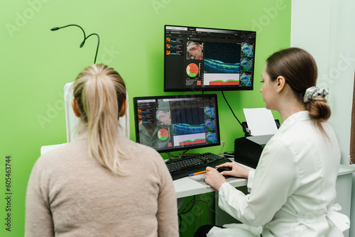 Examination of eyes of patient using optical coherence tomograph. Optical coherence tomography OCT scan to create pictures of the back of eye. Ophthalmologist is scanning cornea of woman patient.
