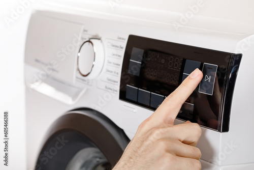 The hand select settings for laundry on modern digital display. Close-up view of automatic washing machine with touch screen on control panel. Press start or pause