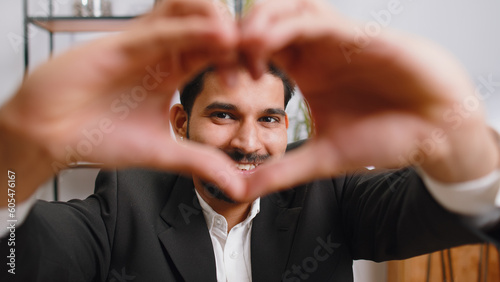 I love you. Indian business man makes symbol of love, showing heart sign to camera, express romantic feelings, express sincere positive feelings at home office workplace. Charity, gratitude, donation
