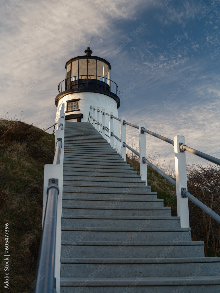 Vertical image looking up towards the Owls Head Lighthouse in Maine with the gray steps in the foreground