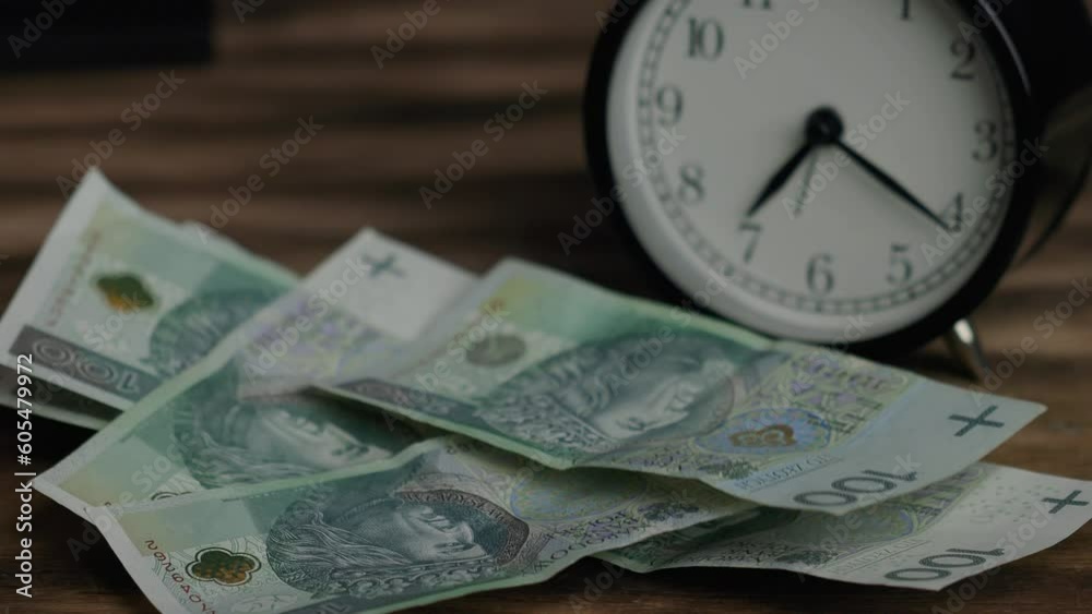 PLN banknotes, Polish zlotys, thrown on the table, clock in the background PLN banknotes, Polish zlotys, thrown on the table, clock in the background
