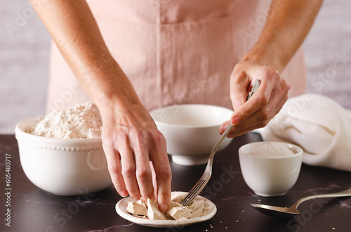 Young woman in a pink apron starting to knead with flour and yeast. Cooking process.