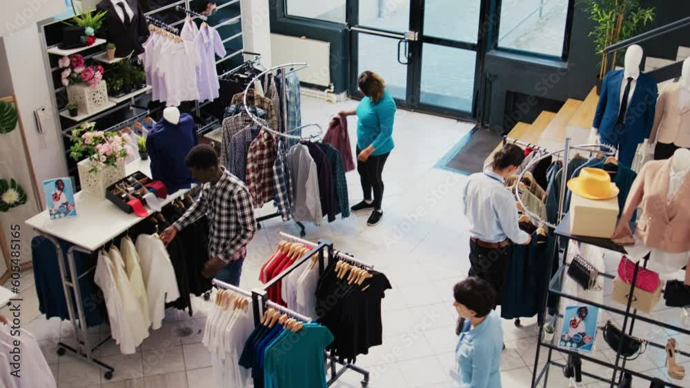 Top view of diverse customers checking stylish clothes, shopping for fashionable merchandise and accessories in modern boutique. Clients analyzing hangers with new fashion collection Top view of diverse customers checking stylish clothes, shopping for fashionable merchandise and accessories in modern boutique. Clients analyzing hangers with new fashion collection