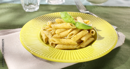 Penne Pasta with Pesto Sauce. green background. traditional Italian dish. camera movement at an angle. frame close ap.