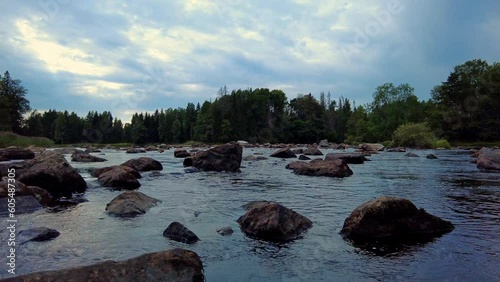 Beautiful evening shot of boulders scattered in the Dalälven river. Blue sky covered with clouds. Real time 60 fps for slow motion static shot low angle view. Färnebofjärden National Park Sweden