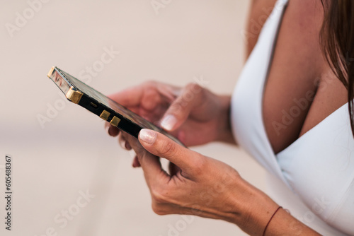 vista desde cerca de mujer agarrando su celular  tecleando  marcando su tel  fono  con sus dedos con luz natural