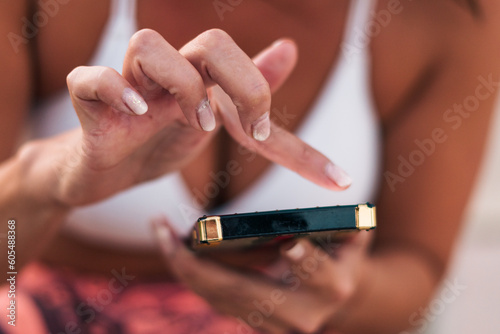 vista desde cerca de mujer agarrando su celular  tecleando  marcando su tel  fono  con sus dedos con luz natural.