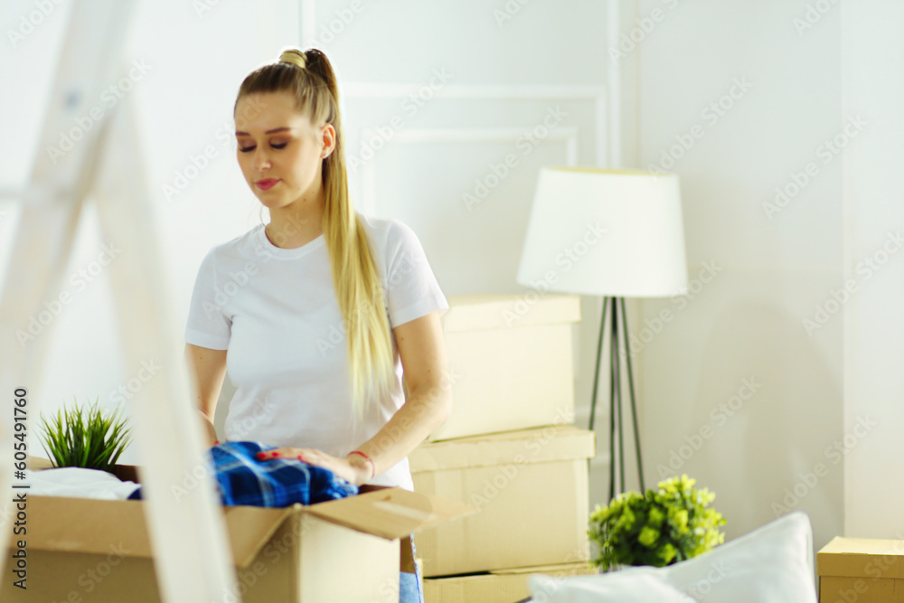 A beautiful single young woman unpacking boxes and moving into a new home. A women look at here tablet A beautiful single young woman unpacking boxes and moving into a new home. A women look at here tablet