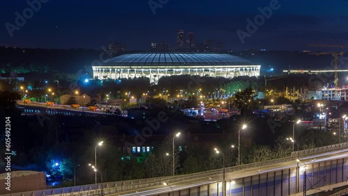 Aerial view of illuminated Luzhniki Stadium and complex from rooftop timelapse, Moscow, Russia at night. Traffic on the highway road. Close up view