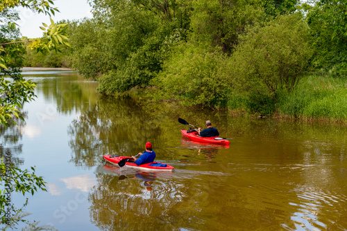 Men Paddling Kayaks On The River In Spring