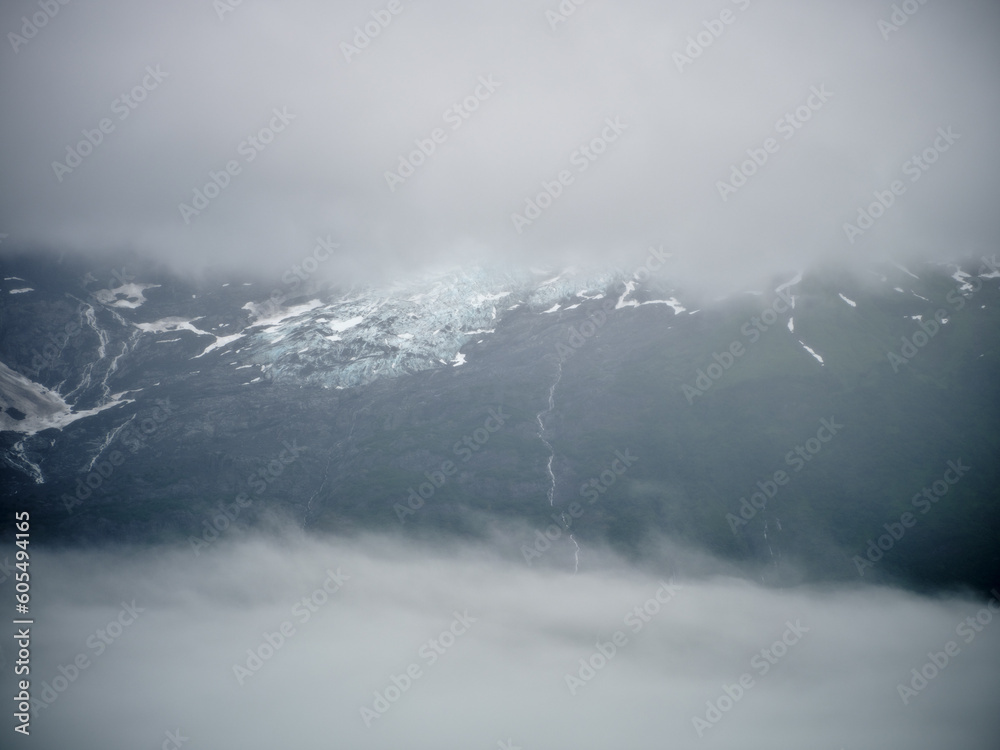 Low lying fog and clouds envelope the glaciers and the mountains on Prince William sound near Whittier Alaska