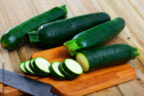 Image of cut raw green zucchini on wooden surface in kitchen