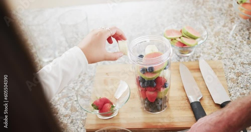 Midsection of caucasian couple preparing heathy smoothies in kitchen, slow motion