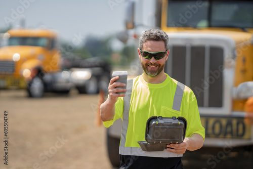 Man driver with lunch box. Truck driver having take away lunch drink coffee to go. Trucker trucking owner. Transportation industry vehicles. Handsome man driver front of truck.