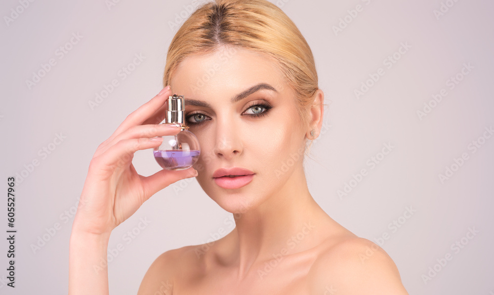 Beautiful romantic tender girl using perfume. Woman with bottle of perfume. Woman presents perfumes fragrance. Perfume bottle, spray aroma. Woman holding a perfumes bottle.
