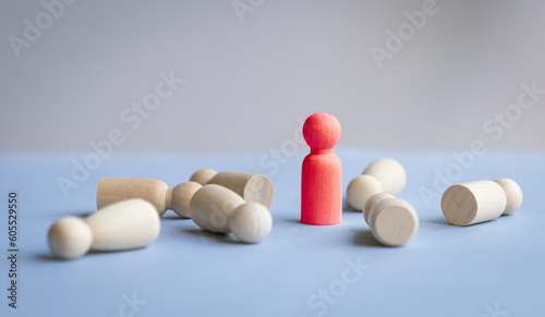 Red wooden doll standing with the rest fallen on desk. Leadership or talent search concept.