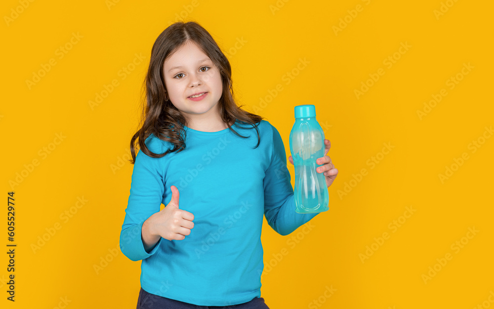 positive child with sport bottle on yellow background. thumb up positive child with sport bottle on yellow background. thumb up