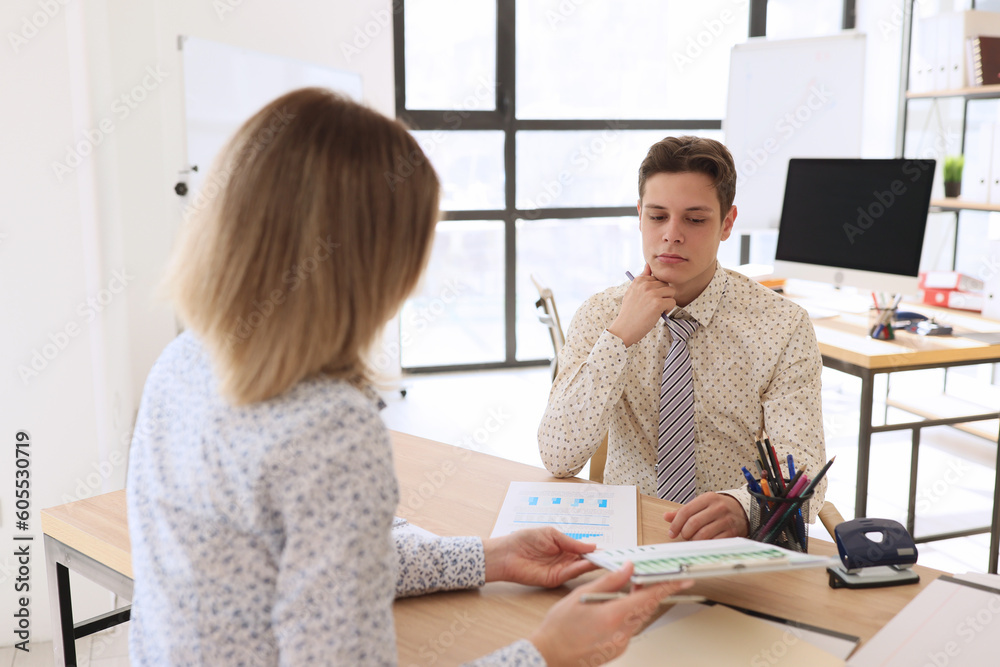 Woman shows charts and statistics on clipboard to colleague Woman shows charts and statistics on clipboard to colleague