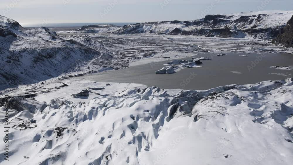 Drone clip moving backwards showing vast snowy landscape with central lake and river gorge carved by glaciers in Iceland Drone clip moving backwards showing vast snowy landscape with central lake and river gorge carved by glaciers in Iceland