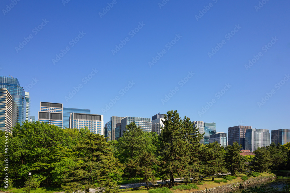 A view of the Otemachi and Marunouchi office districts through the fresh green trees from the Shiomizaka slope of the Imperial Palace. Taken April 2023.