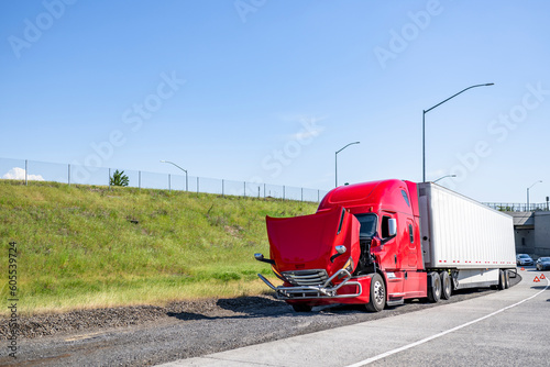 Red broken big rig semi truck with open hood standing on the road shoulder out of service