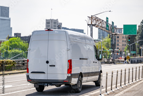 Spacious commercial cargo mini van making delivery driving on the urban city street
