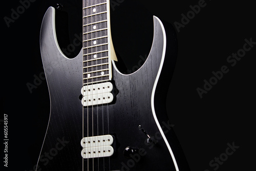 black electric guitar body with strings and frets with pick up on black background photo