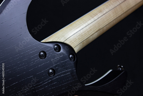 black electric guitar body back with strings and frets with pick up on black background photo