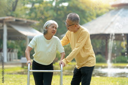 Husband helps his elderly wife use a walker to learn to walk elderly couple Asian elderly couple giving love to each other smiling happily love and care for each other