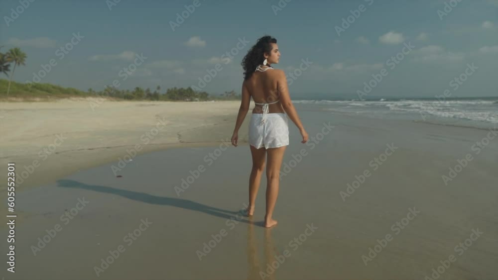 beautiful brown skin girl with cute curls walking the beach with shimmering sun along the ocean sea water. turning around to the camera, sunny. beautiful brown skin girl with cute curls walking the beach with shimmering sun along the ocean sea water. turning around to the camera, sunny.